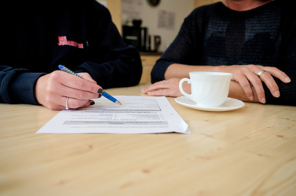 Eine Sozialarbeiterin der Johanniter hilft einer Klientin ein Formular auszufüllen.