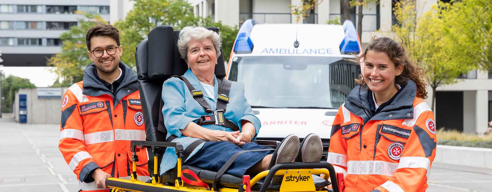 Zwei ehrenamtliche Sanitäter:innen transportieren eine Patientin auf einer Fahrtrage.