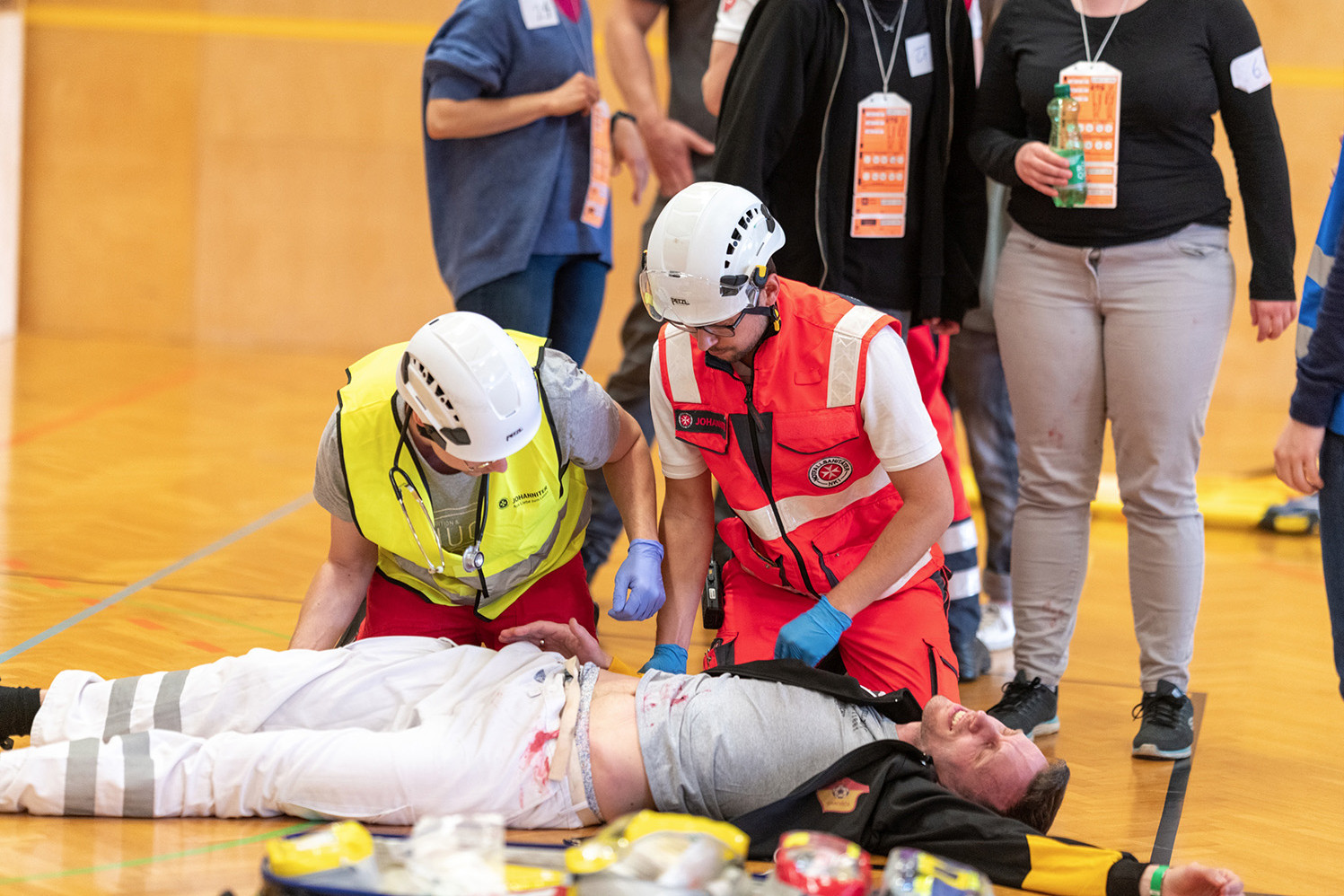 Ein Notarzt und ein Sanitäter helfen einer verletzten Person, die am Boden liegt.