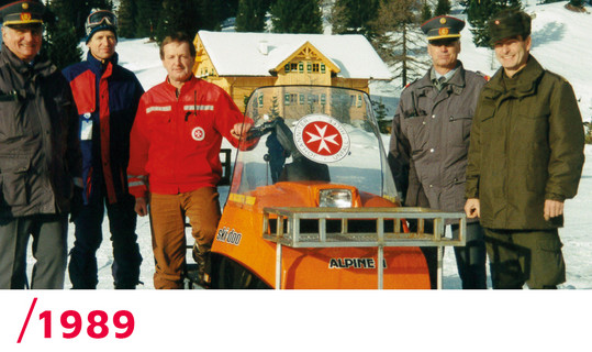 1989: Ein Johanniter, Polizisten und Schifahrer neben einem Ski-Doo des Johanniter-Pistendienstes