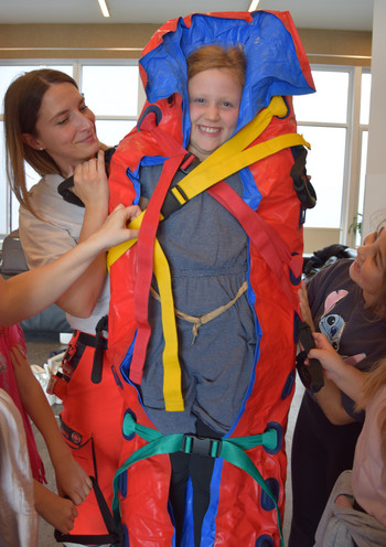 Eine Johanniterin legt eine Schülerin in eine Vakuum-Matratze.