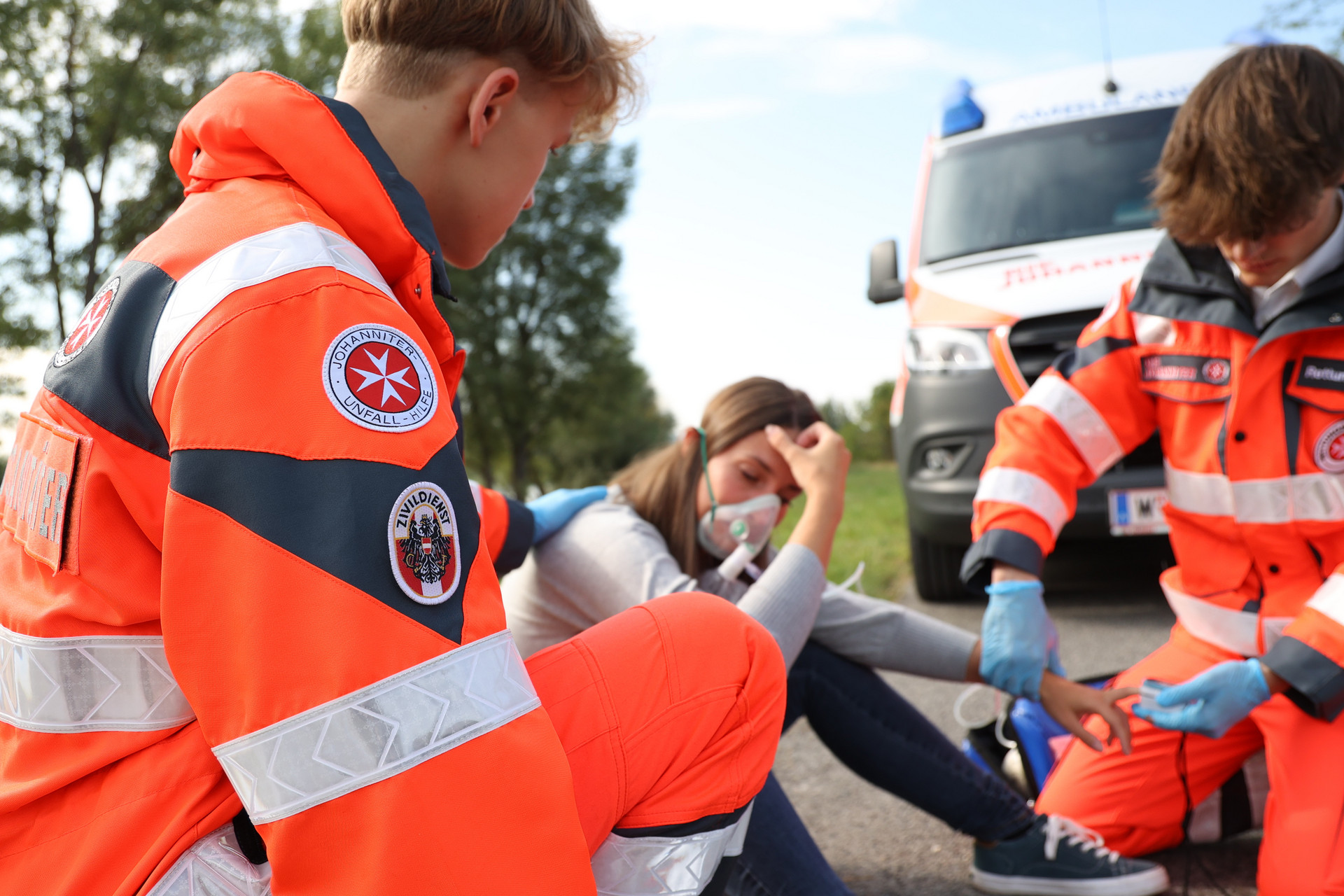 Zwei Zivildiener kümmern sich um eine Frau, die mit Sauerstoffmaske am Boden sitzt.