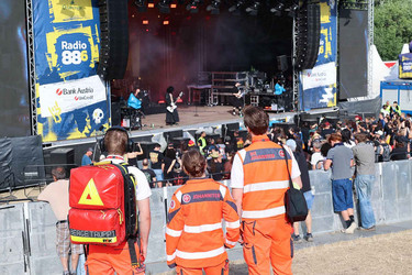 Drei Johanniter schauen beim Donauinselfest auf die Rock-Bühne, wo sie den Ambulanzdienst betreuen.