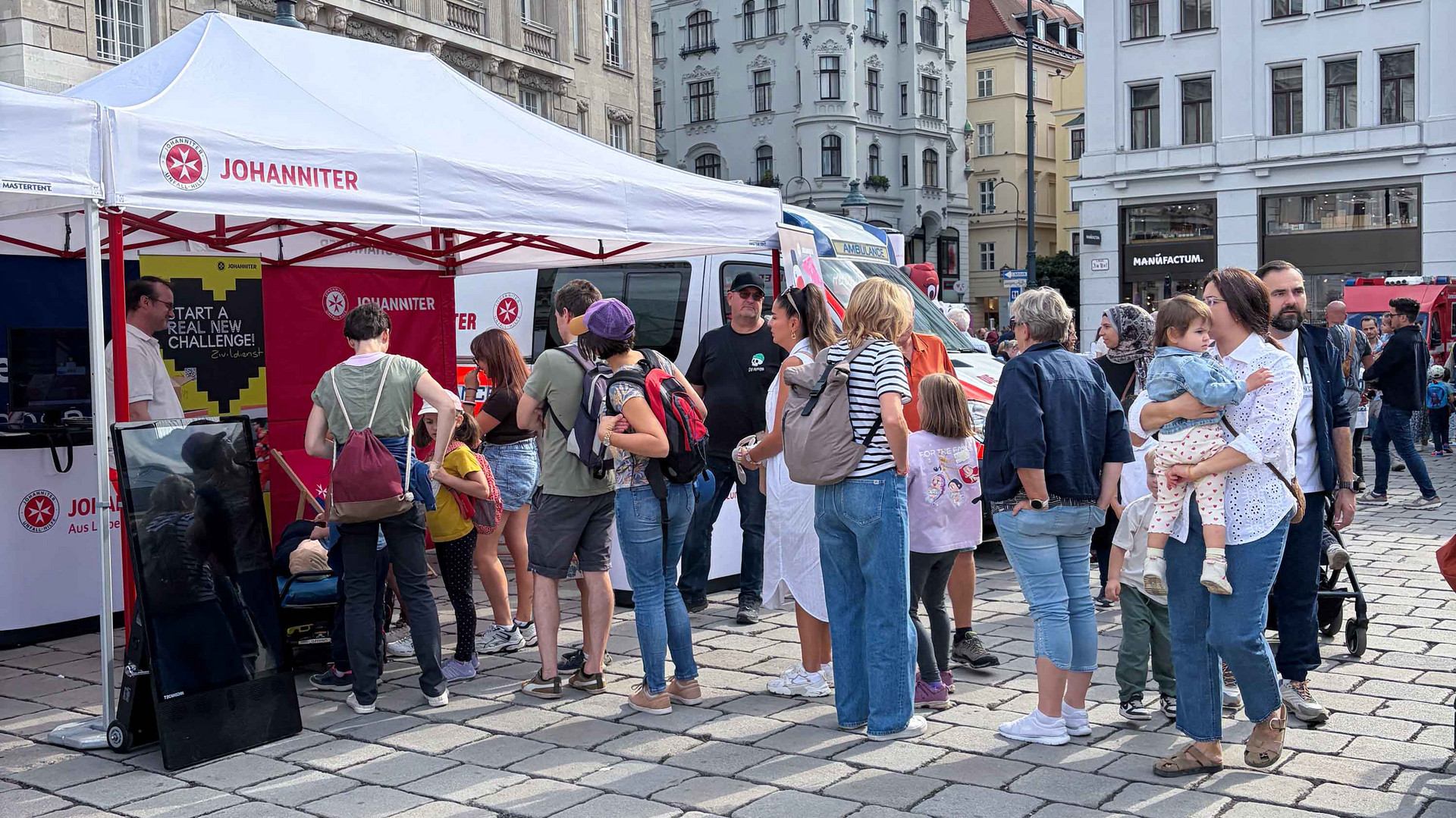 Vor dem Zelt der Johanniter steht eine Menschentraube.