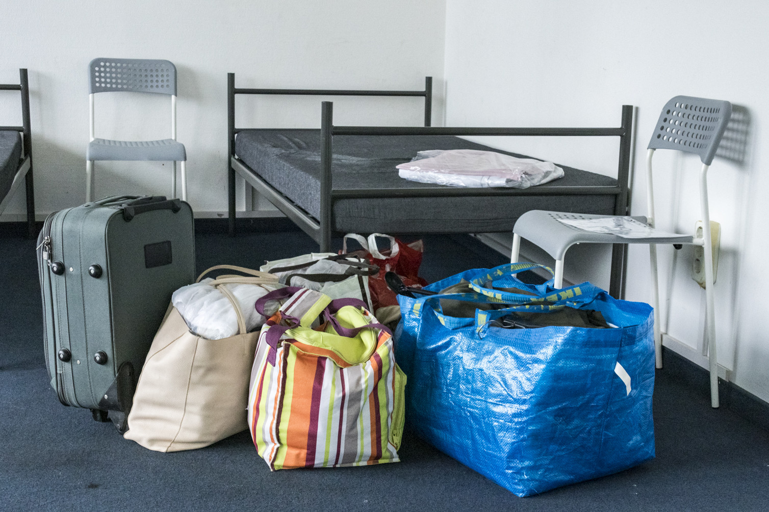 Gepäckstücke stehen vor einem Bett in einer Notunterkunft.