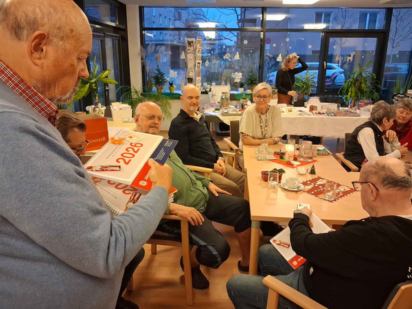 Die Bewohner:innen der Residenz bekommen die Tischkalender für 2026 überreicht.