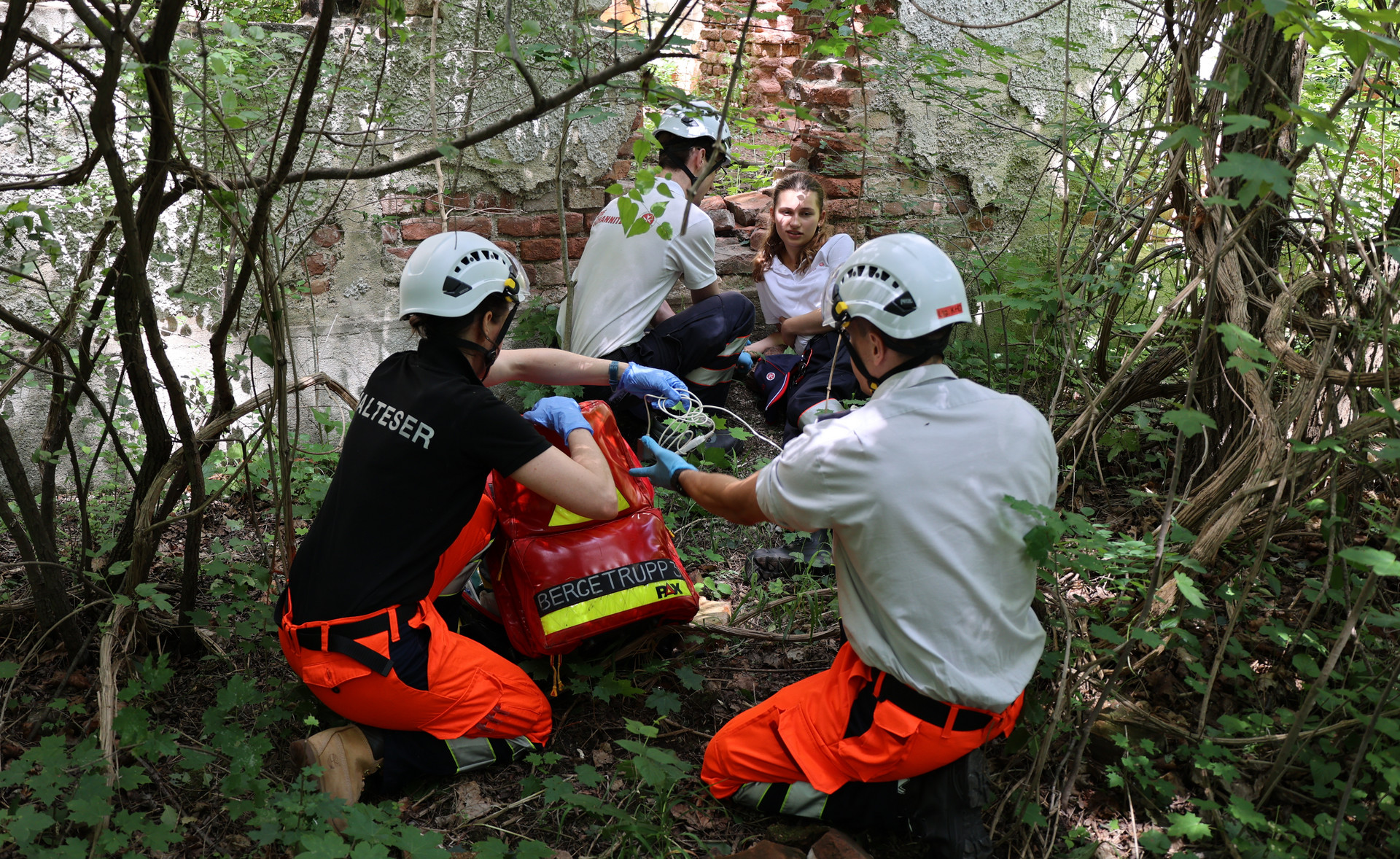 Drei Einsatzkräfte haben eine verletzte Frau bei einer Mauer im Wald gefunden.