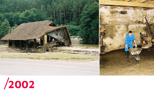 2002: Ein in sich zusammengefallenes Haus und ein Johanniter, der bei den Aufräumarbeiten in einem gefluteten Haus hilft.