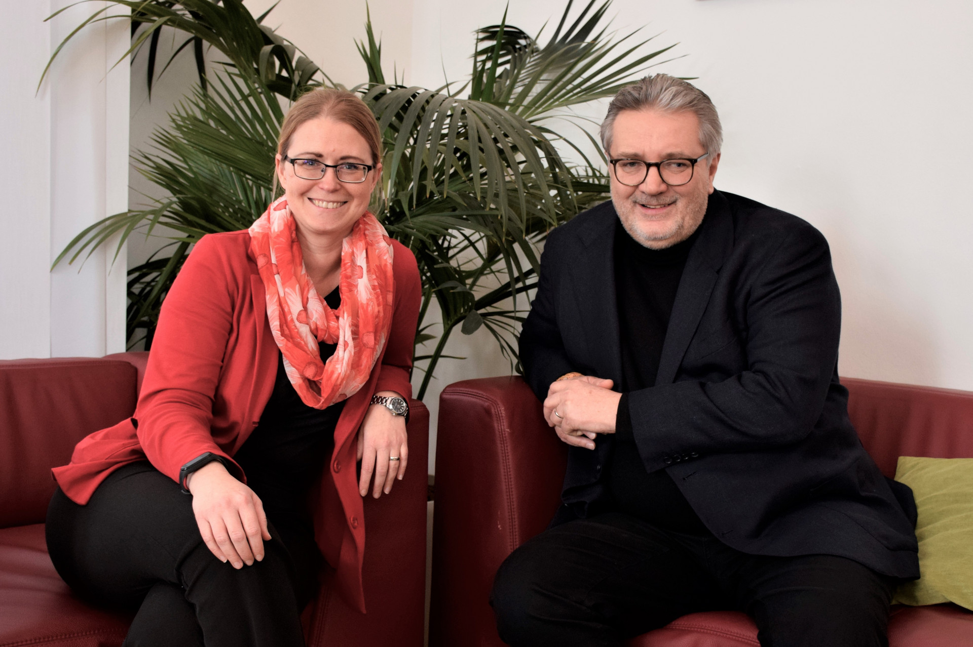 zwei Personen sitzen auf einem Sofa, sie lächeln in die Kamera, links Bundesgeschäftsführerin der Johanniter Petra Grell-Kunzinger und rechts Stadtrat Peter Hacker