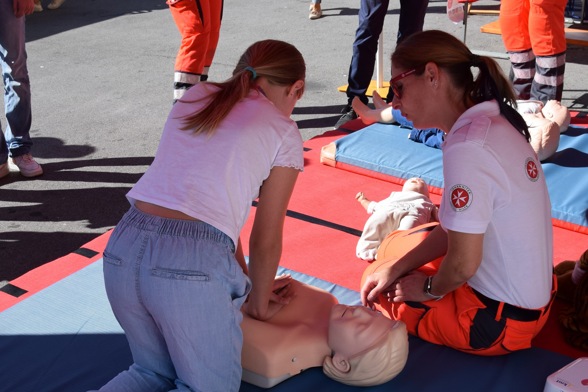 Ein Mädchen übt die Reanimation an einer Puppe.