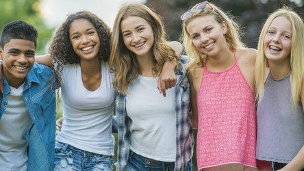 Eine Gruppe von Jugendlichen steht nebeneinander und lächelt in die Kamera.