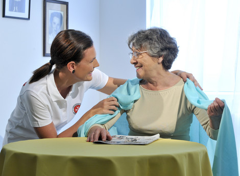Eine Pflegerin des Palliativteams legt der Patientin eine Decke um die Schultern.