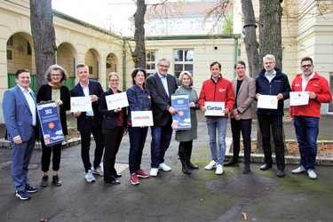 Vertreter:innen aller Partnerorganisationen des Winterpakets halten je ein Schild mit dem Logo ihrer Organisation hoch.