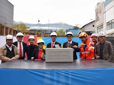 Eine Gruppen an Johannitern und Bauträgern mit dem Grundstein des "Johanniter Center Tirol"