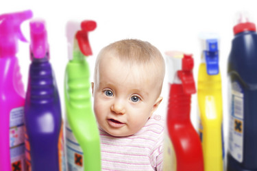 Ein Baby zwischen Flaschen mit Putzmittel
