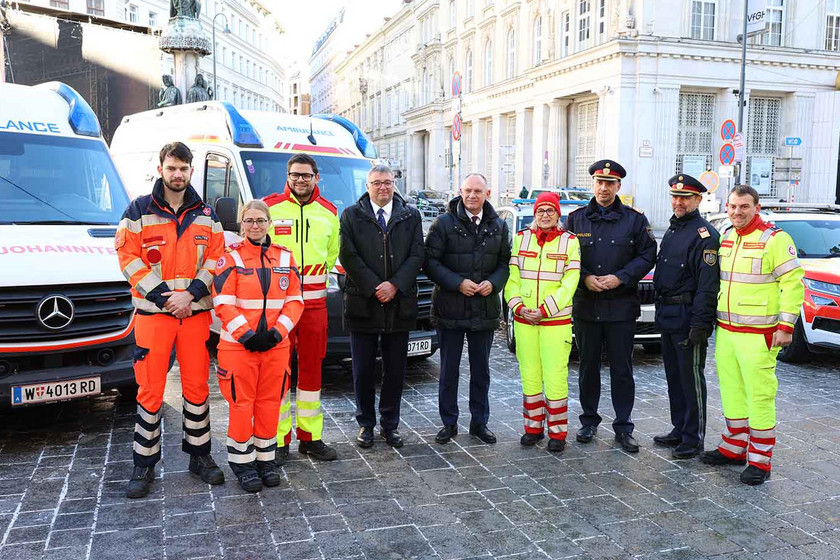 Die "Vier für Wien" stehen gemeinsam mit Polizei und Vertretern der Politik vor Rettungsautos.