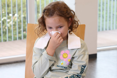 Ein Mädchen mit Nasenbluten hält sich ein Taschentuch unter die Nase.