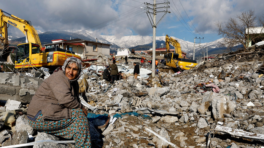 unglückliche Frau sitzt auf den Trümmern eines zerstörrten Hauses