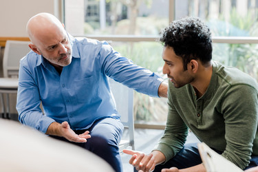 Ein älterer Mann spricht einem anderen Mann gut zu.
