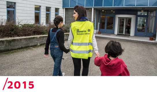 2015: Eine Ehrenamtliche geht mit zwei geflüchteten Kindern an der Hand in die Notunterkunft in Wien.