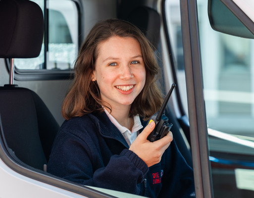 Eine Johanniterin vom FSJ sitzt am Beifahrersitz mit einem Funkgerät in der Hand.