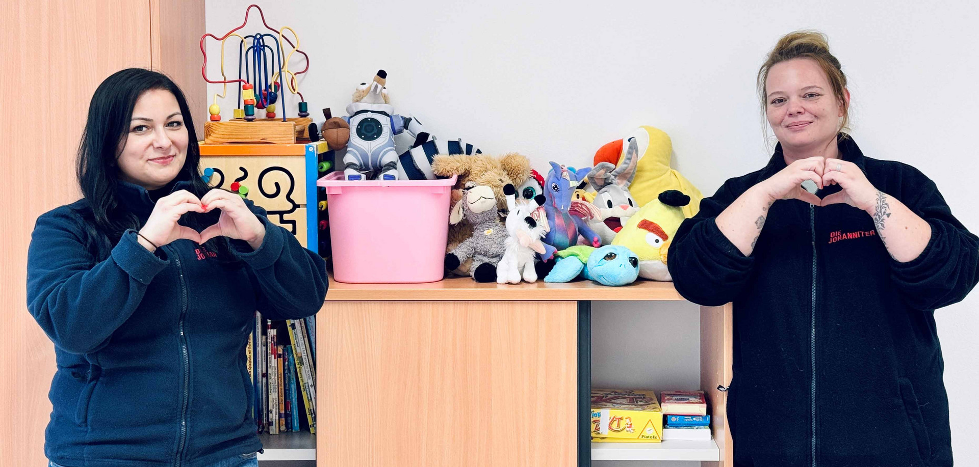 Zwei Betreuerinnen zeigen ein Herz in die Kamera, als Danke-Zeichen für die Spielzeugspenden