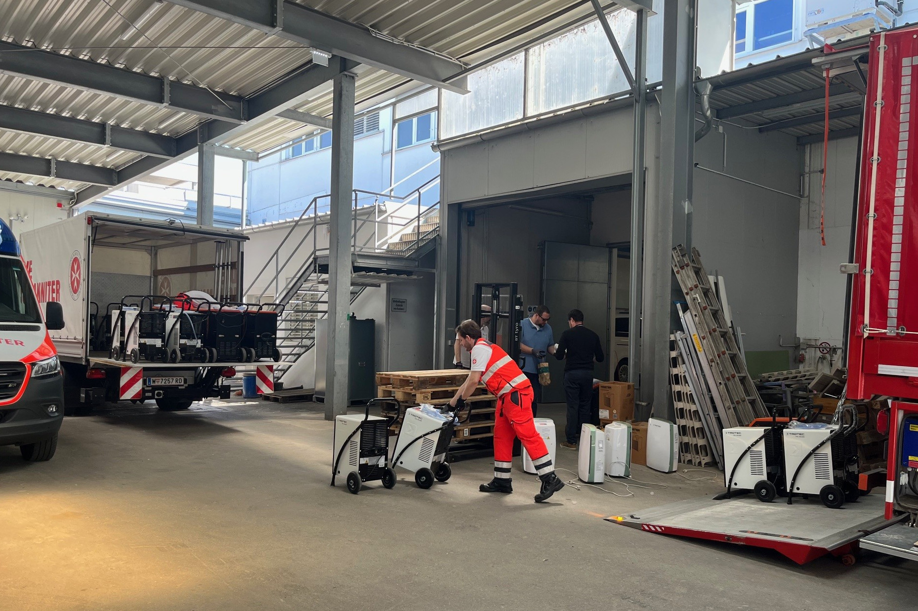 Trocknungsgeräte werden aus den LKW von einem Johanniter ausgeladen.