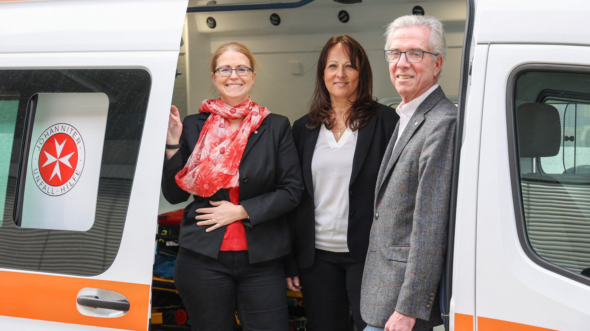 Bundesgeschäftsführerin Petra Grell-Kunzinger, Geschäftsführerin Wien-NÖ Karin Zeiler-Fidler und Johanniter Präsident Johannes Bucher stehen in einem Krankenwagen.