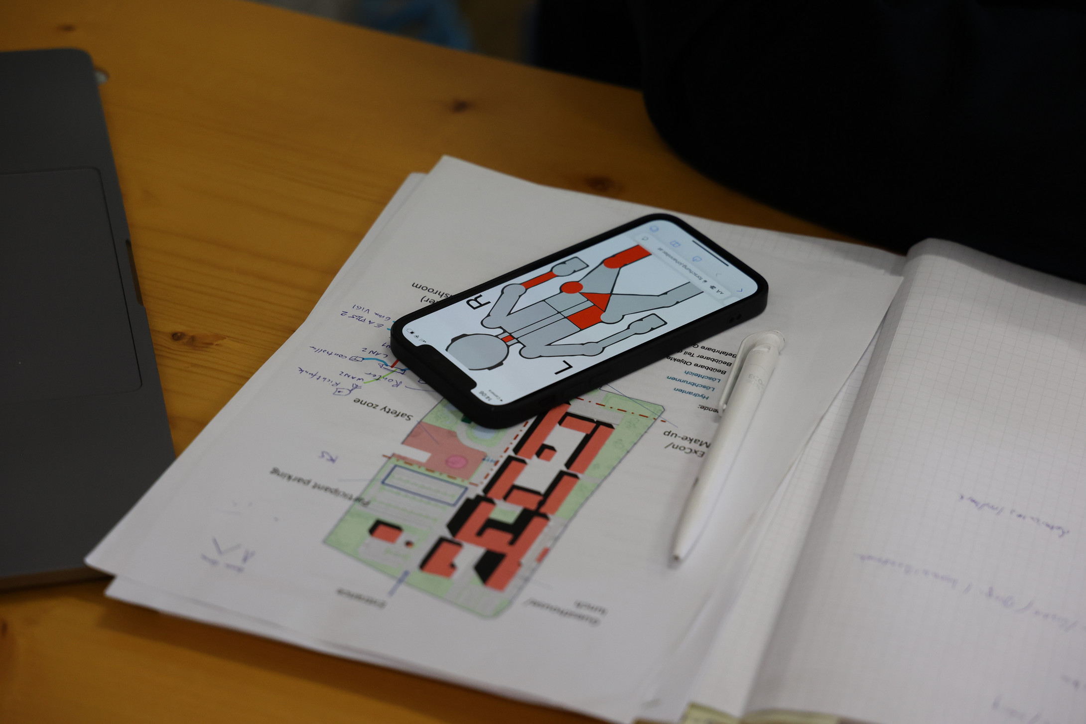 Ein Handy mit einem Patientenleitsystem liegt auf einem Zettel, wo ein Lageplan dargestellt ist.