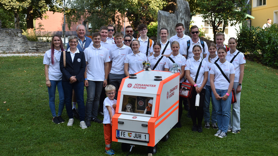 Die Johanniter Jugend steht rund um ihr selbst gebautes Mini-Rettungsauto.