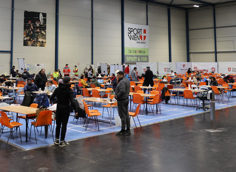 In der Sport & Fun Halle wurden viele Tische aufgestellt, wo Leute essen und zur Ruhe kommen.