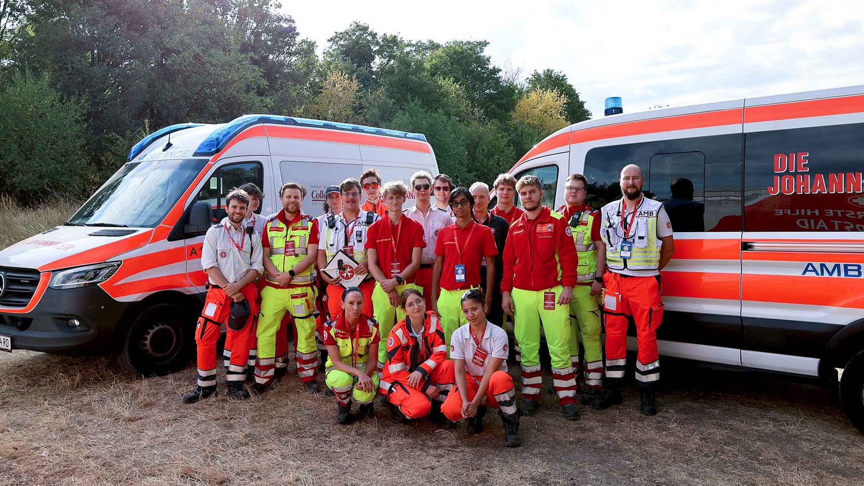 Das Team aus Sanitäter:innen von Johannitern und Samaritern vor zwei Johanniter Rettungsautos.