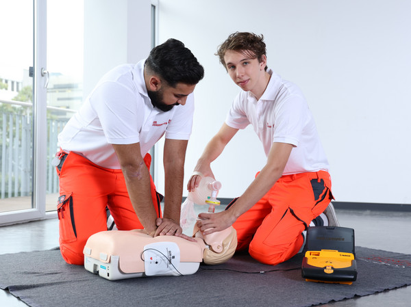 Zwei Zivildienstleistende üben an einer Puppe die Reanimation mit Defibrillator.
