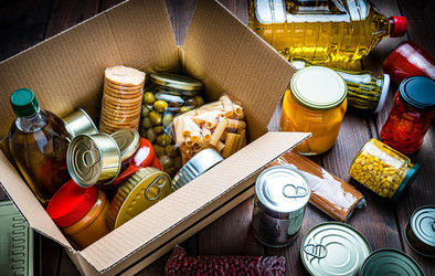 Ein Karton mit lange haltbarem Essen: zum Beispiel Dosen, eingelegtem Gemüse, Nudeln und Öl