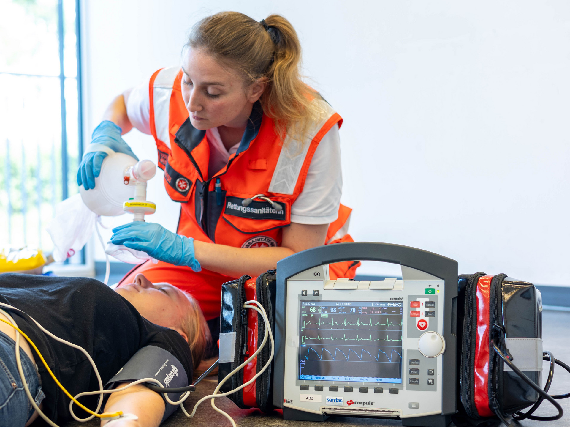 Eine Rettungssanitäterin beatmet mit einem Beatmungsbeutel. Die Patientin ist am Corpuls angeschlossen.