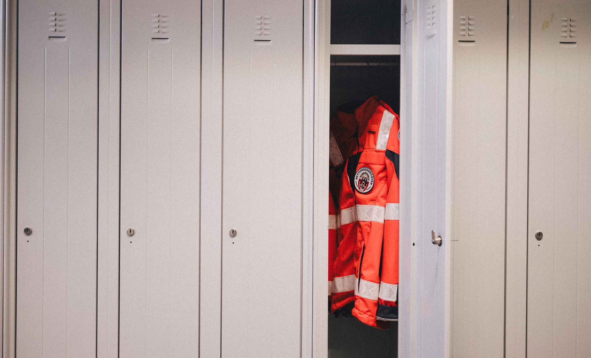 Eine Johanniter-Uniformjacke hängt in einem Spind.