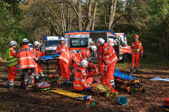 Eine Gruppe von Sanitätern versorgt bei einer Übung im Wald die verletzten Personen.