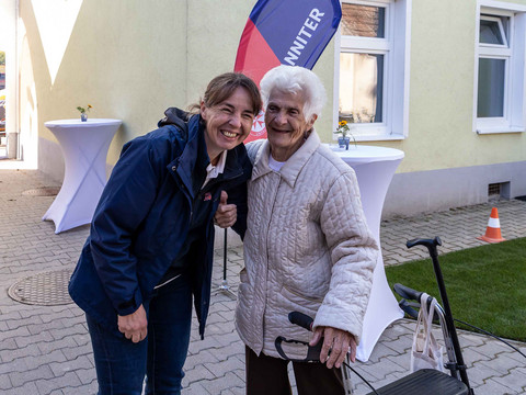 Die Community Nurse und eine Dame mit Rollator lachen in die Kamera.