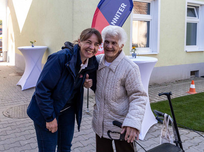 Die Community Nurse und eine Dame mit Rollator lachen in die Kamera.