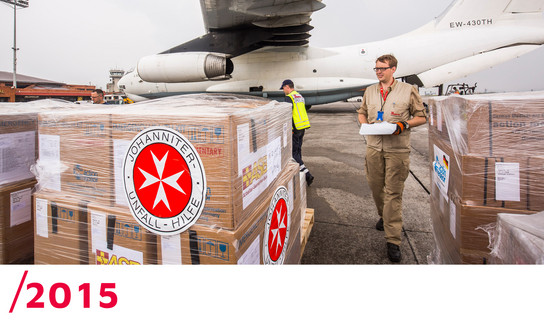 2015: Ein Helfer überprüft die Hilfspakete, die vor einem Flugezeug stehen.