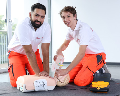 Zwei Zivildienstleistende üben an einer Puppe die Reanimation mit Defibrillator.