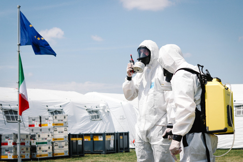 Zwei Personen in Schutzanzügen geben einen Funkspruch ab.