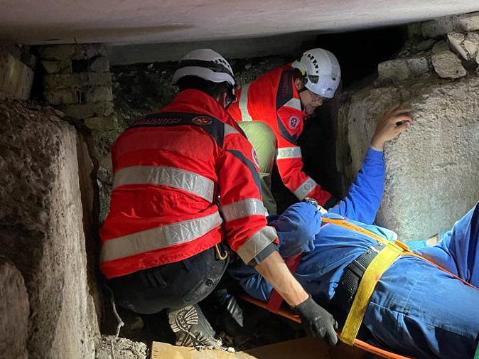 drei Sanitäter retten einen Verletzten aus einem dunklen Bunker
