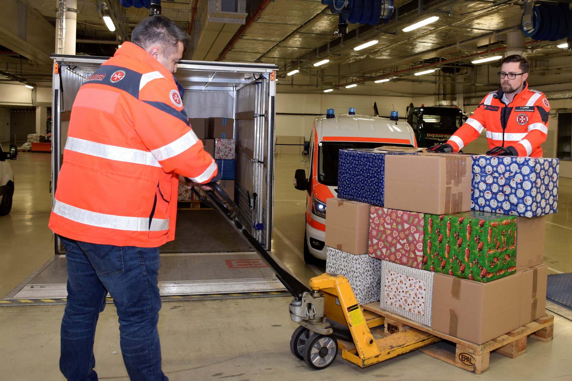 Zwei Johanniter beladen einen LKW mit Hilfspaketen.