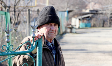 Ein älterer Mann sitzt bei kalten Temperaturen draußen.