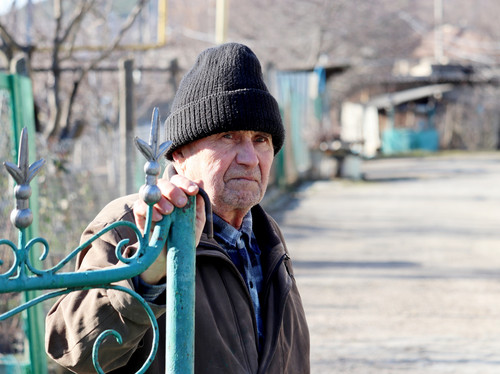 Ein älterer Mann sitzt bei kalten Temperaturen draußen.