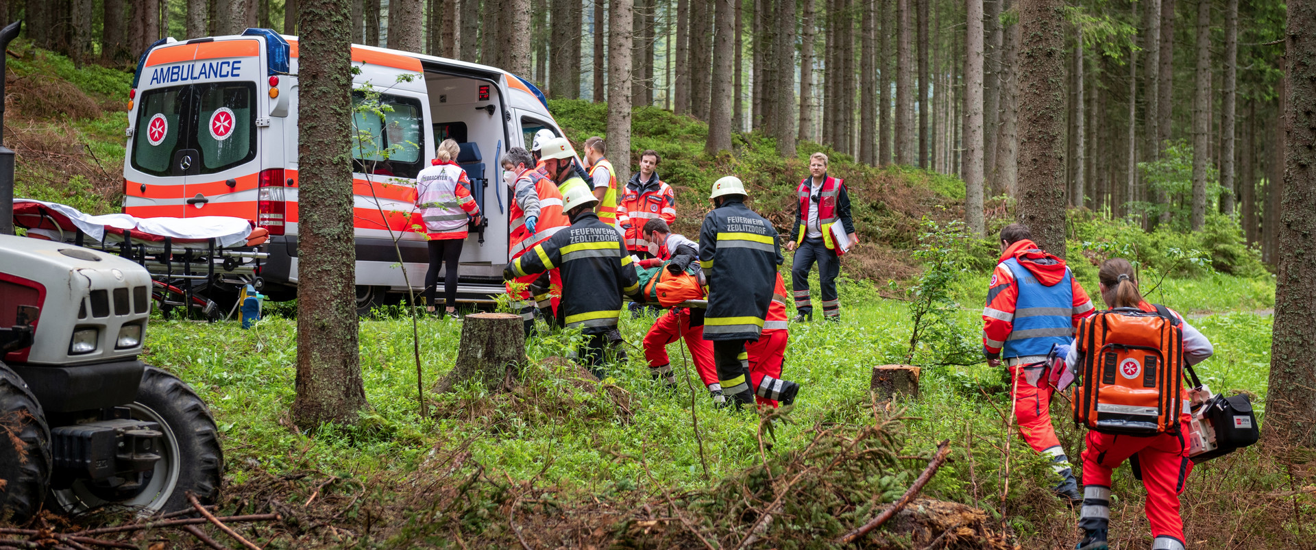 Johanniter und Feuerwehr bergen bei einer Übung gemeinsam eine verunglückte Person aus dem Wald.