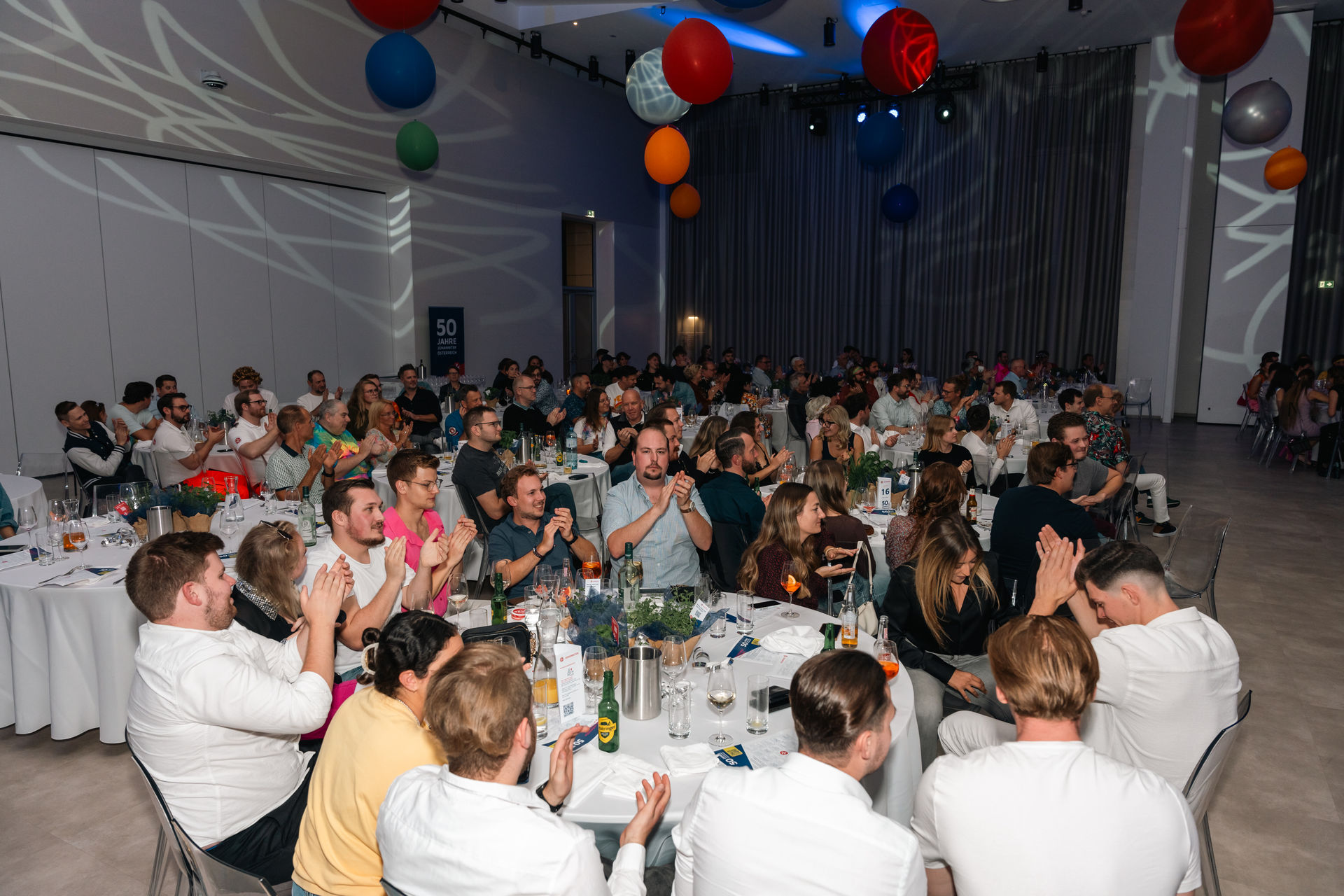 Viele Menschen sitzen im Veranstaltungsraum und klatschen
