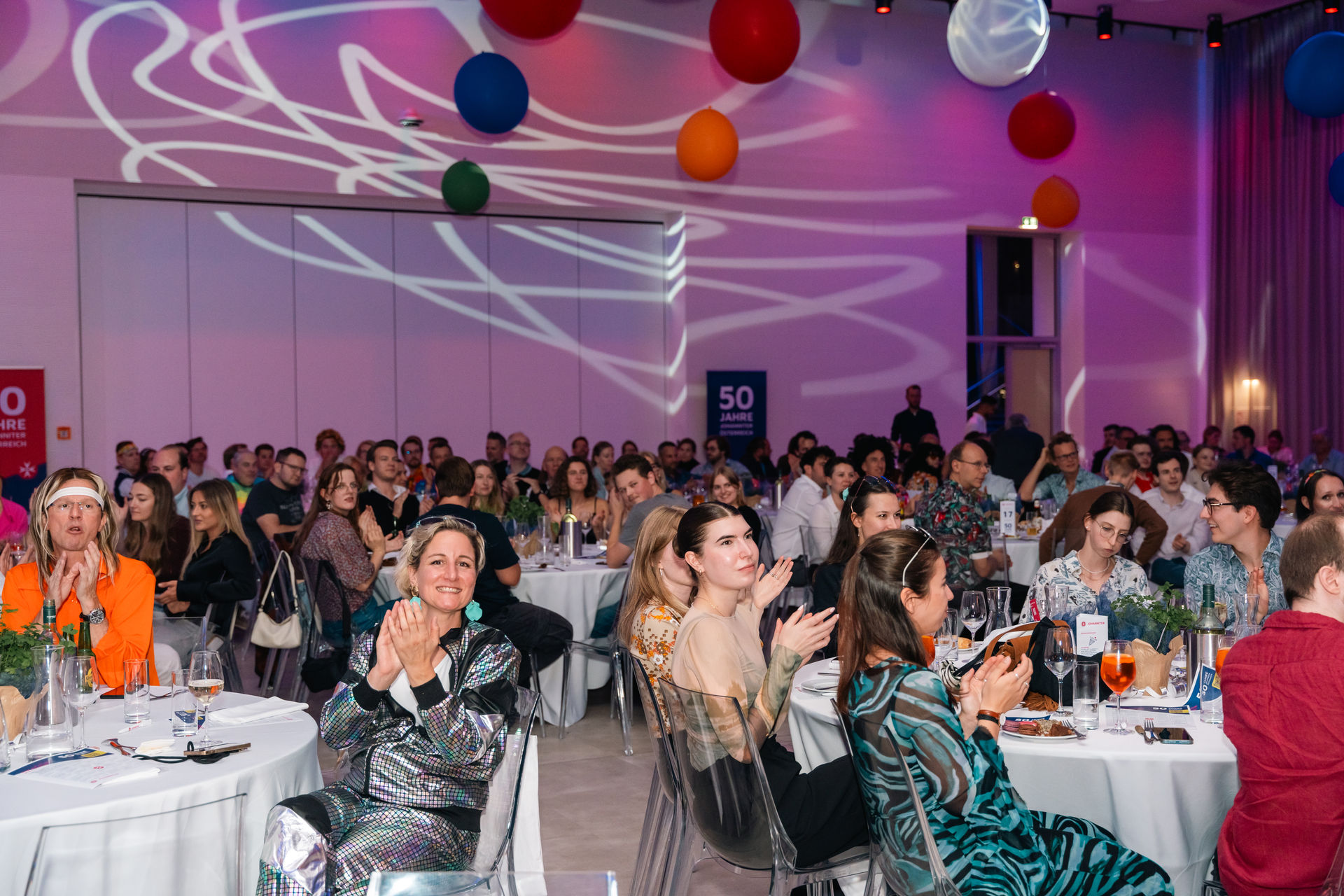 Viele Menschen sitzen im Veranstaltungsraum und klatschen