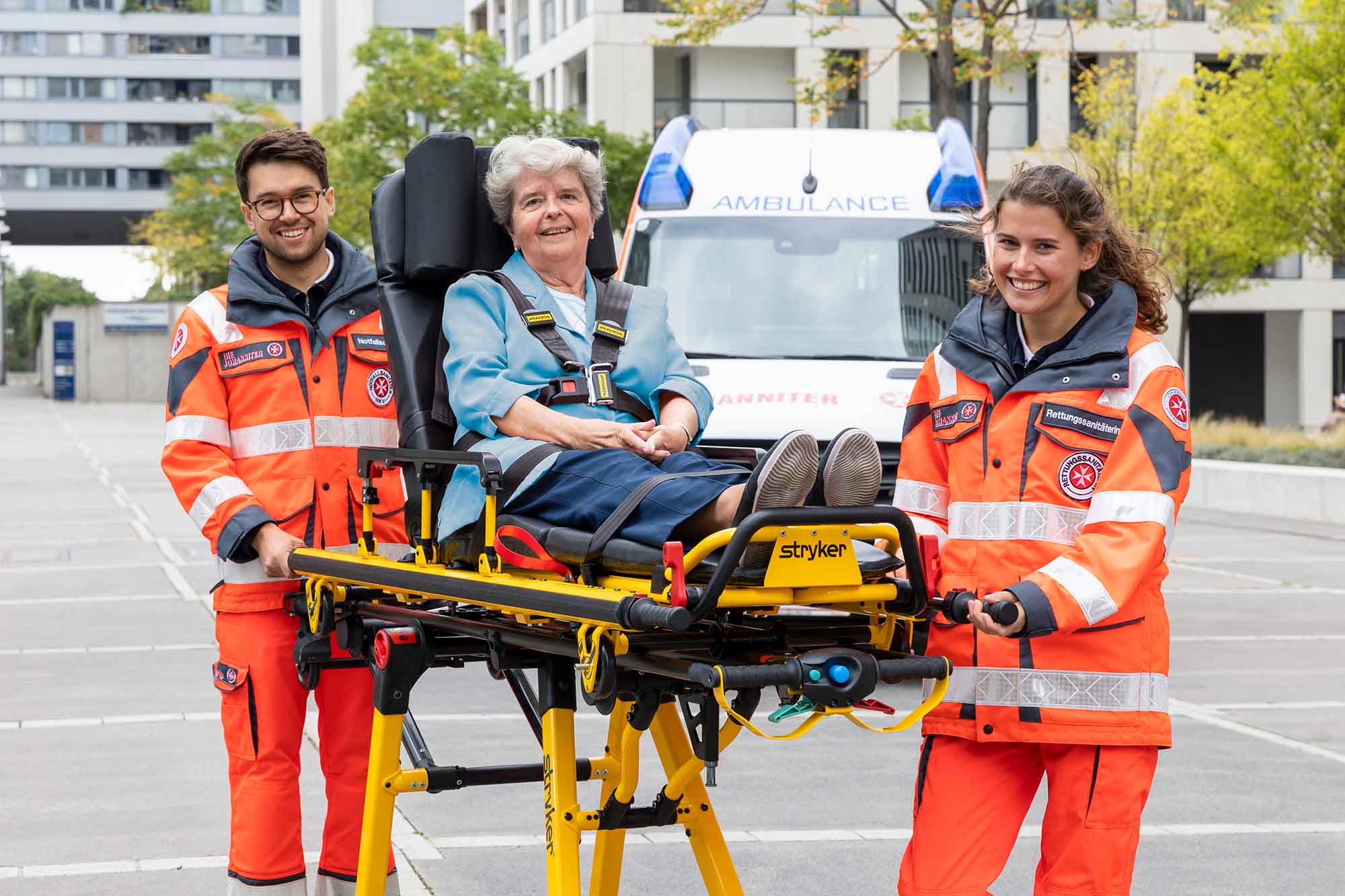 Zwei ehrenamtliche Sanitäter:innen transportieren eine Patientin auf einer Fahrtrage.